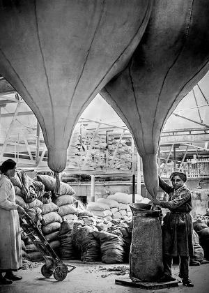 黑白照片，两个女人在一家工厂装石棉袋
