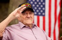 美国二战老兵在背景中向美国国旗敬礼