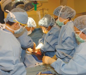 外科医生戴着口罩和蓝色的手术服给病人做手术