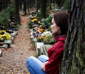一个女人在墓地的一棵树旁悲伤